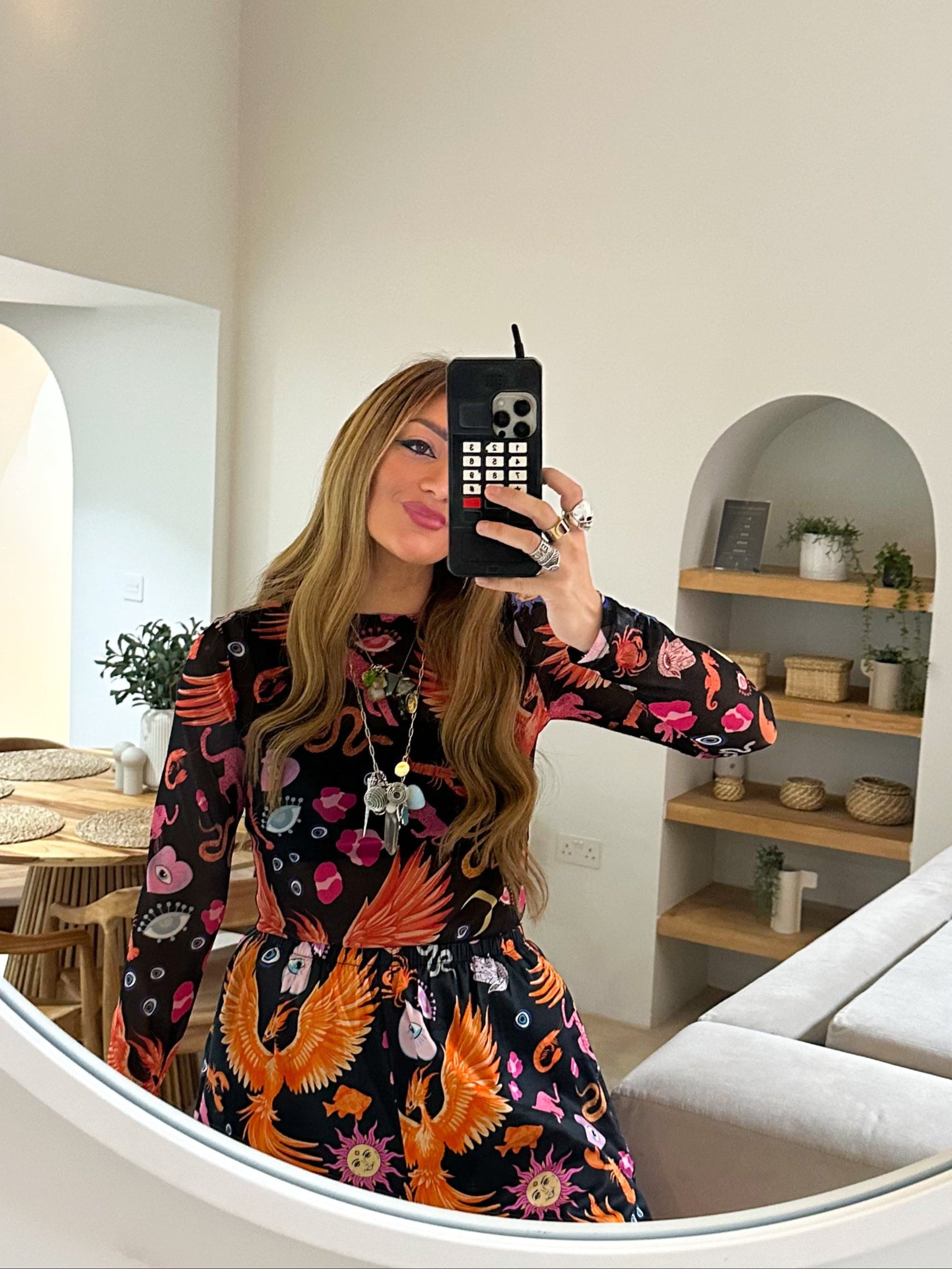 Woman taking a mirror selfie in a modern living room.