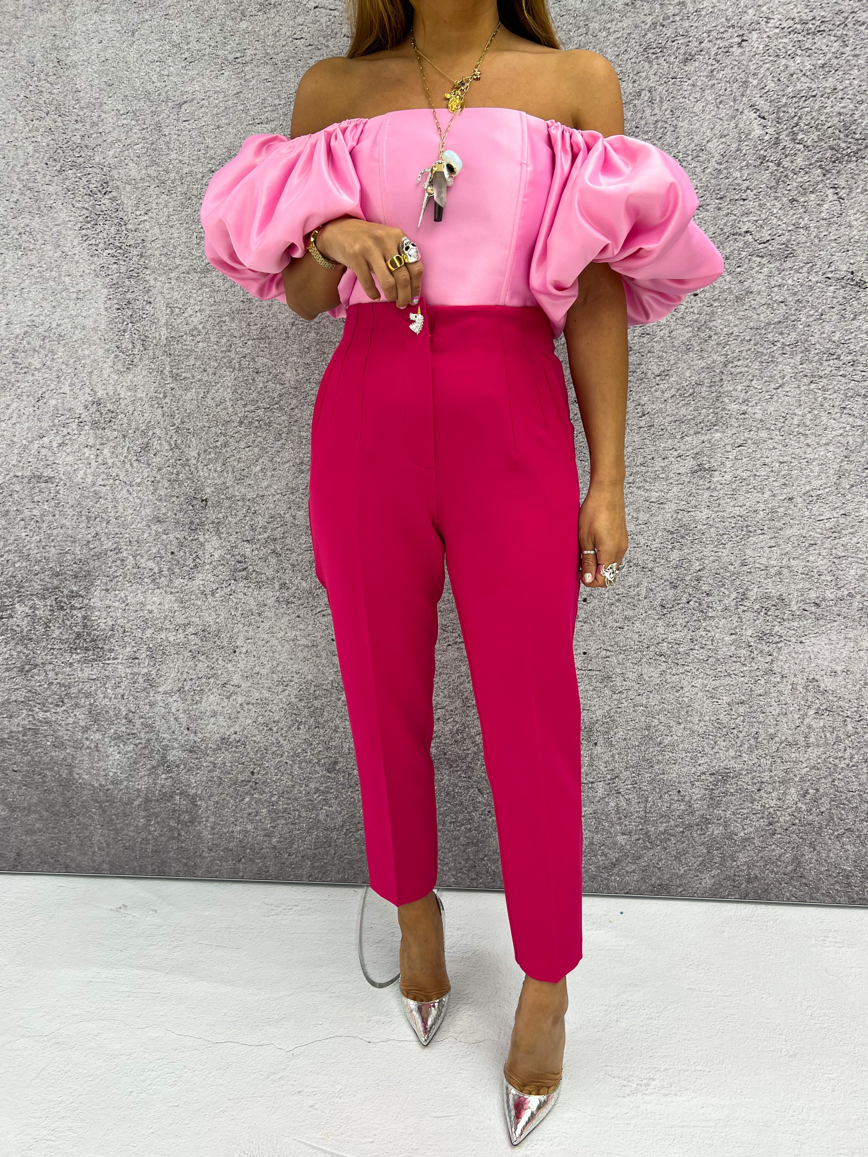 a model wearing an off-the-shoulder pink top with puffed sleeve styled with a pink tailored trousers