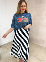 Model wearing a tie dye oversized graphic t-shirt featuring a AC/DC band logo, styled with a black and white horizontal stripe