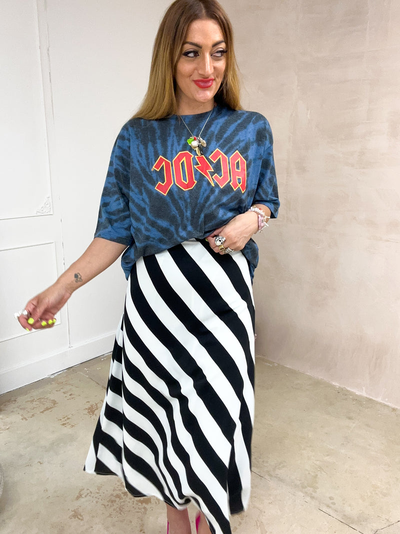 Model wearing a tie dye oversized graphic t-shirt featuring a AC/DC band logo, styled with a black and white horizontal stripe