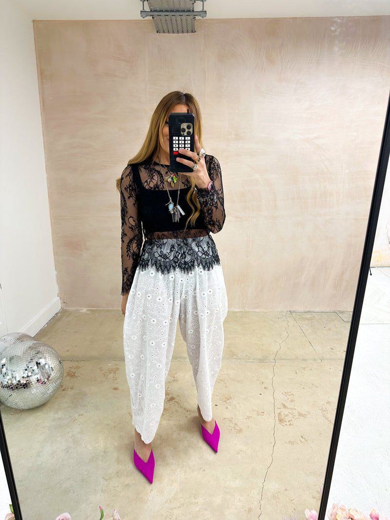 mirror selfie of model wearing Broderie Anglaise Balloon Trousers In White styled with long sleeve lace top in black 