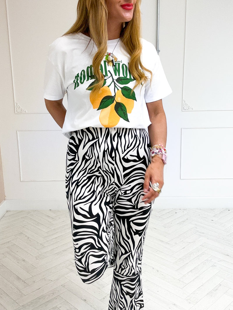 model wearing High Waisted Flared Trousers In Zebra Print styled with graphic t-shirt in white 