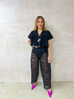 model wearing Embroidered Pleated Hem Swing style cropped Top In Black with t-shirt style sleeves styled with ballon lace trousers in black 