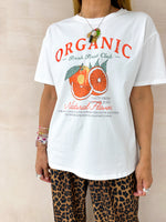 close up of a model wearing a white t-shirt with sliced orange graphics styled with leopard print trousers