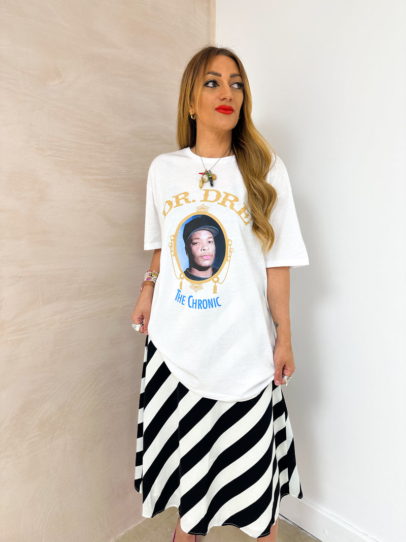 model wearing oversized t-shirt in white with Dr. Dre 'The Chronic' graphics, styled with horizontal stripe skirt in black and white