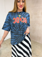 Model wearing a tie dye oversized graphic t-shirt featuring a AC/DC band logo, styled with a black and white horizontal stripe