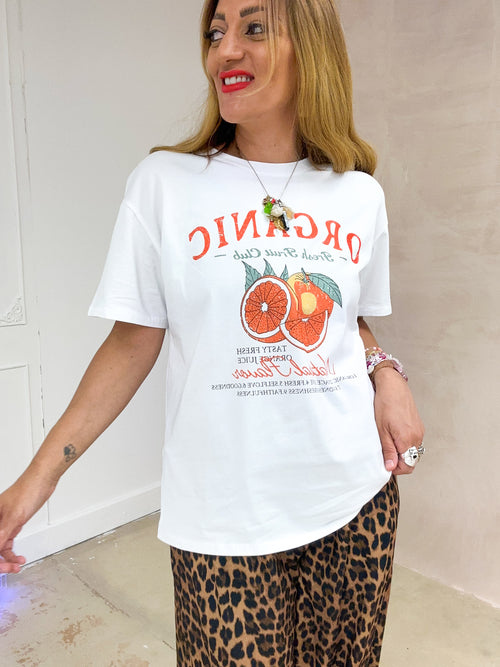 close up of a model wearing a white t-shirt with sliced orange graphics styled with leopard print trousers