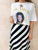 model wearing oversized t-shirt in white with Dr. Dre 'The Chronic' graphics, styled with horizontal stripe skirt in black and white