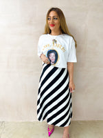 model wearing oversized t-shirt in white with Dr. Dre 'The Chronic' graphics, styled with horizontal stripe skirt in black and white