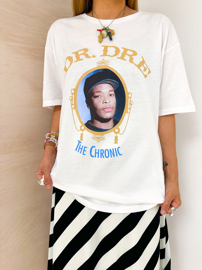 close up of model wearing oversized t-shirt in white with Dr. Dre 'The Chronic' graphics, styled with horizontal stripe skirt in black and white