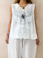 close up of model wearing floral Embroidered sleeveless Vest Top In White styled with Broderie Anglaise Balloon Trousers In White